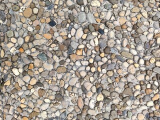 A textured surface of variously shaped and colored pebbles arranged closely together