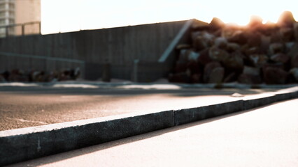 Sunlight casts long shadows on a concrete surface as the day transitions to night. The urban landscape features rough textures, hinting at nearby construction and a serene atmosphere.