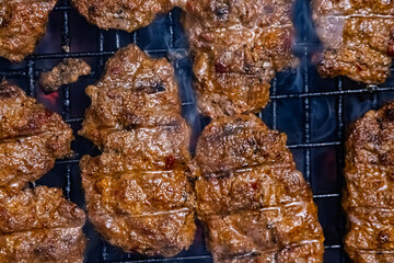 Top view of juicy grilled meat patties sizzling on a barbecue grill with smoke and char marks. Representing delicious summer cookout, outdoor barbecue and savory homemade grilled food texture.