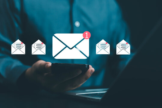 Businessman using smartphone with digital email notification icons, representing online communication, message alert, and email marketing in modern business technology and digital networking.