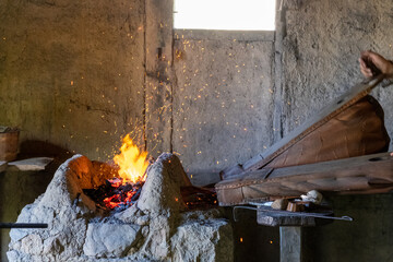 Schmiedebalg, der Luft in eine Esse mit Flammen bläst