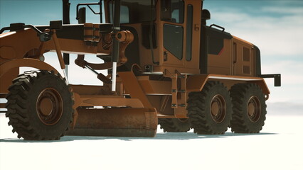 A large motor grader is maneuvering across a flat, open area. The machines powerful wheels dig into the surface as it prepares the ground for upcoming construction activities.