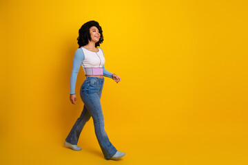 Naklejka na ściany i meble Young stylish woman walking confidently against vibrant yellow background, wearing a trendy outfit, joyful and fashionable Naklejka na ściany i meble Young stylish woman walking confidently against vibrant yellow background, wearing a trendy outfit, joyful and fashionable
