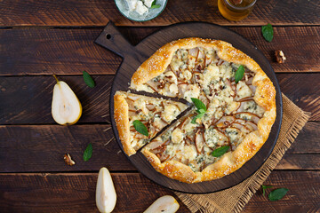 Homemade pear brie galette on wooden board, golden crust, melted cheese, honey glaze. Sliced galette with pear and bri cheese