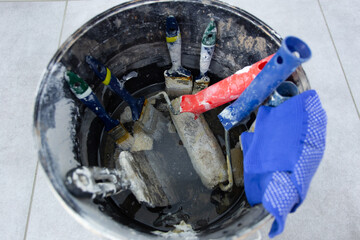 Dirty painter's tools after work in a bucket of solvent.