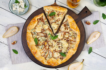 Homemade pear brie galette on wooden board, golden crust, melted cheese, honey glaze. Sliced galette with pear and bri cheese