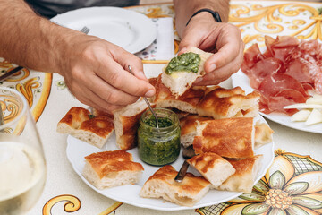 Hand reaching for freshly baked bread with green pesto sauce 