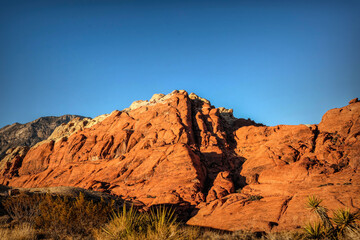 Vibrant Red Sandstone Peaks Rise Majestically Against Azure Skies in Red Rock Canyon's Ancient Desert Embrace, Nevada