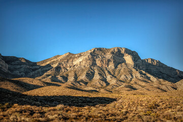 Majestic Crimson Sandstone Spires Pierce Azure Nevada Skies, Unveiling Ancient Desert Layers in Red Rock Canyon's Timeless, Sun-Drenched Embrace