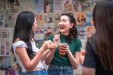 Friends chatting outdoors while enjoying iced beverages and street snacks, showing casual social gathering, Asian lifestyle, friendly atmosphere and candid happy moments in urban setting