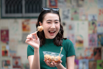 Young woman eating shumai street food with an excited expression, showing Asian cuisine, casual lifestyle, fun food experience, culture, candid emotion and tasty urban snack outdoors