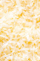 A full-frame, top-down view of a pile of freshly shredded cheese, displaying its texture and golden-yellow color. Perfect for food-related projects and backgrounds.