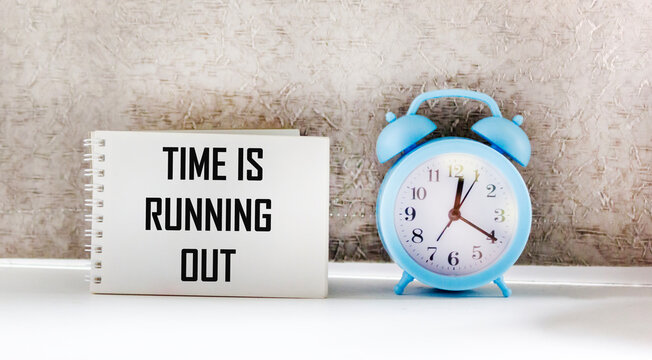 Alarm clock and notepad with the inscription "time is running out", highlighted on a light background
