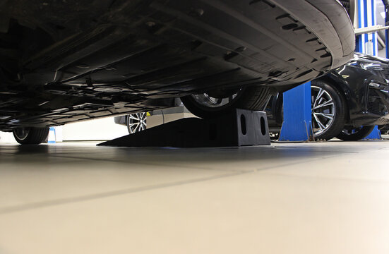 Engine crankcase guard is attached to the bottom of a car raised on special stoppers in a garage 
