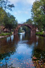 A historic stone arch bridge spans a calm, clear river