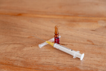 Impfstofffläschchen und Injektionsspritze auf Holztisch
