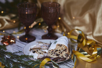 Atmospheric Christmas dinner with Christmas stollen, chocolate and two glasses. Holidays decorations. Aesthetic traditions atmosphere background. Copy space