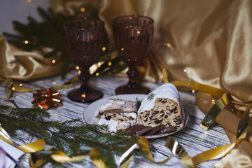 Atmospheric Christmas dinner with Christmas stollen, chocolate and two glasses. Holidays decorations. Aesthetic traditions atmosphere background. Copy space