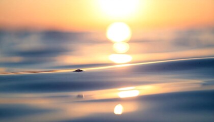 Golden sunset reflecting on tranquil water with a blurred sun and a hint of a boat