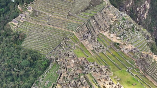 A close-up, downward-facing shot begins in the industrial zone of Machu Picchu, then flies smoothly over the site to reveal the intricate patterns of the ancient cultivation and agricultural terraces
