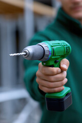 Man holding a green cordless drill at a construction site