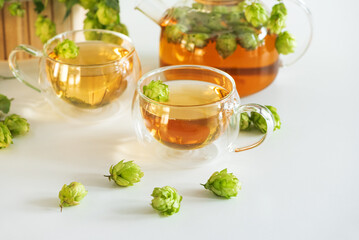 Hop Tea in Glass Teapot and Cups with Fresh Hops on Table