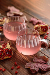 Autumn Beverage: two Cups ofPomegranate Tea with Lemon and Ginger on Rustic Table