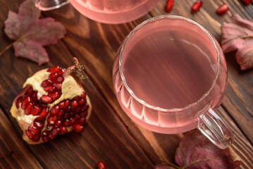Autumn Beverage: two Cups ofPomegranate Tea with Lemon and Ginger on Rustic Table