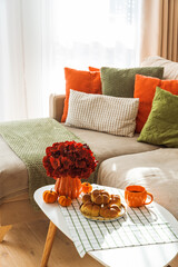 Autumn Living Room with Sofa, Pillows and Pumpkin Cinnamon Buns on Coffee Table