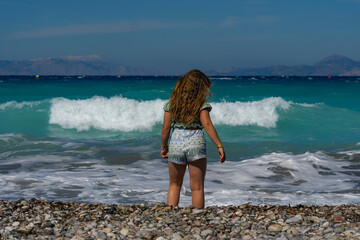 A little girl against the backdrop of the Aegean Sea on a sunny day.