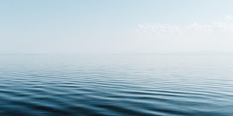 Obraz premium A serene seascape featuring calm waters reflecting a light blue sky with soft clouds, creating a tranquil and peaceful atmosphere.