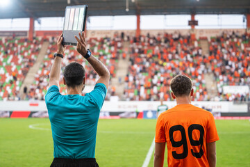 Technical referee shows players substitution during football match.