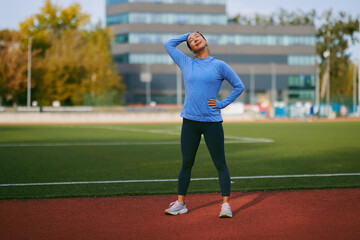 Obraz premium Athlete On Running Track Stretching In Blue Hoodie And Leggings On Outdoor Field