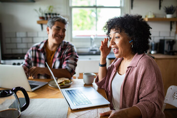 Middle aged couple using laptops at home