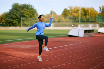 Obraz premium Energetic Woman Jumping and Running on Track During Autumn Outdoor Workout Session