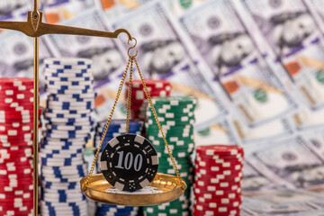 A conceptual story about ludomania (gambling addiction) with a  golden scales and casino betting chips against a background of $100 bills.