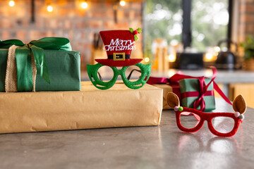 Green glasses topped by red Xmas hat sitting on gifts beside antler glasses on kitchen counter