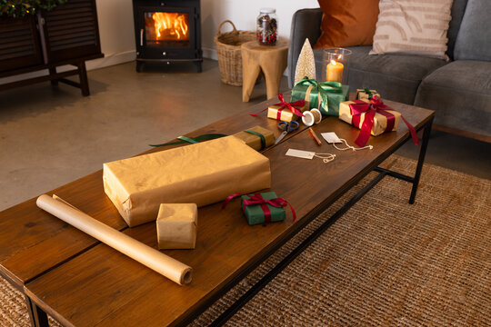 Wrapped gifts and gift tags are lying on wooden coffee table near wood burning stove