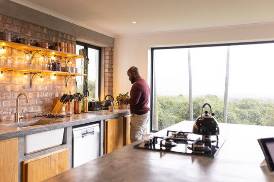 Kitchen featuring brick backsplash and cooktop island hosting kettle by window overlooking trees