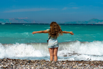 Little girl with outstretched arms against the Aegean Sea. Summer