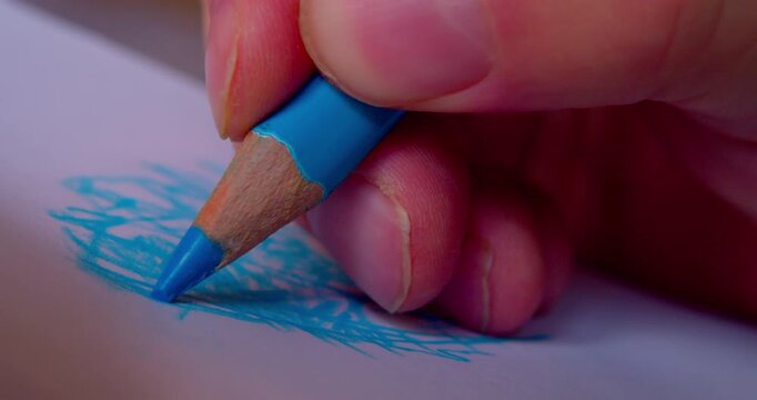 Close-up shot of hand drawing abstract pattern on paper with blue pencil