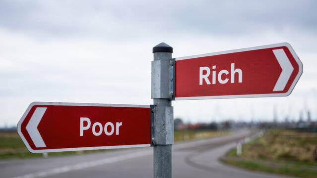 Signpost with red directional arrows labeled rich and poor, economic disparity, choices, decision-making, wealth gap, income inequality, financial direction, crossroads, social status