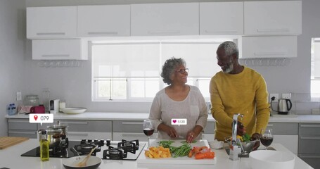 Cooking couple slicing vegetables and rinsing greens at home kitchen island, with cutting board
