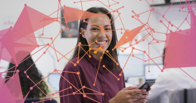 Holding smartphone, woman in maroon blouse interacting with overlay in open-plan office, with PCs