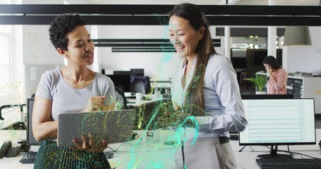 Co-workers holding laptop and displaying holographic interface in open-plan office, reviewing data