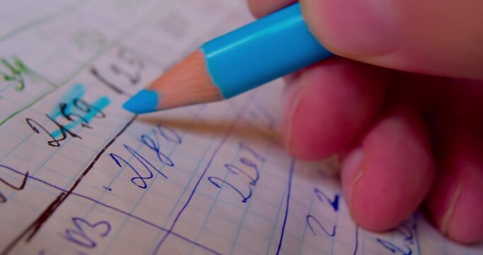 Close-up shot of hand coloring numbers on paper with blue pencil, emphasizing precision and focus in paperwork