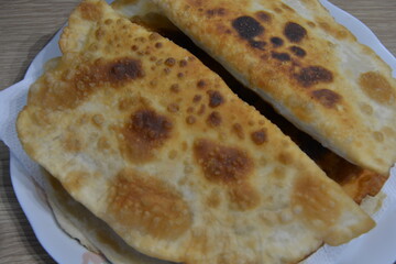 A close-up of golden, crispy fried pastries on a plate. Homemade fried chebureks with a bubbly, appetizing crust