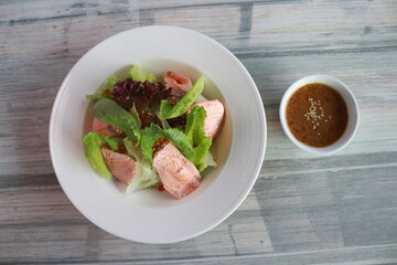Delicious salmon salad with dressing, perfect for a healthy and satisfying meal. The salad is beautifully presented in a white bowl with a side of dressing