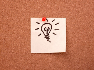 Idea and inspiration concept with a light bulb sketch on a cork board