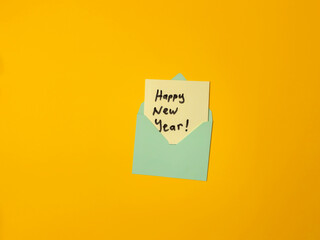 Happy New Year handwritten note in an envelope on a yellow background